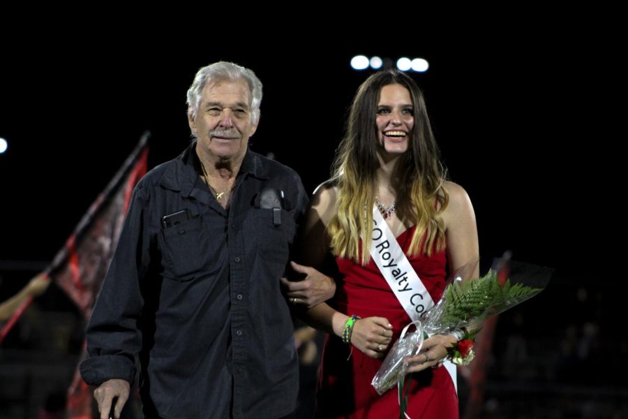 Junior Shae Caroll walks down the football field arm-in-arm with her grandfather as the crowd cheers on. 
