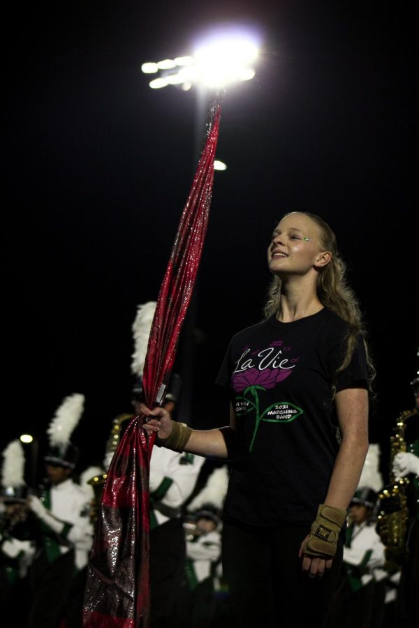 Members of color guard  perform alongside the band in their performance ‘La Vie en Rose.’ At the end of the halftime performance, Senior Elizabeth Hoy smiles and holds her pose, with her flag in hand. 