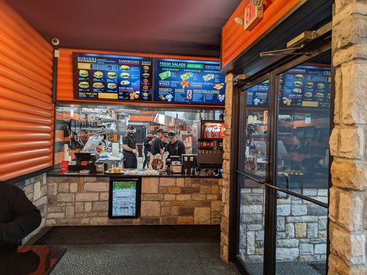 11/11 Homemade Burgers features a Starbucks coffee machine at the cash register. The menu displays many burger options, including chicken sandwiches.