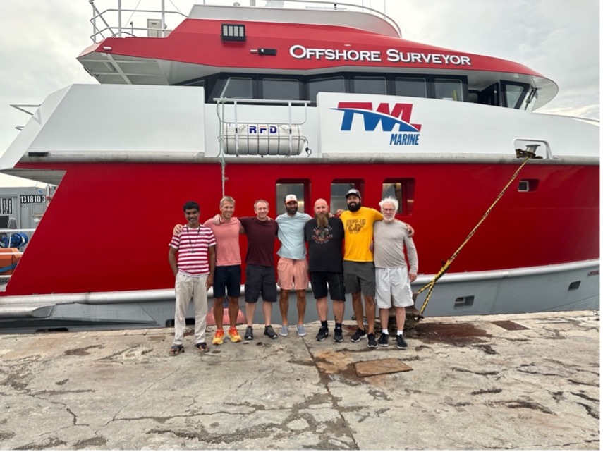 The crew of the RV Offshore Surveyor stand in front of the ship
