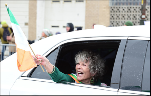A woman holds an Irish flag out of a car window during the Detroit St. Patricks Day parade (courtesy of https://www.detroitstpatricksparade.com/)
